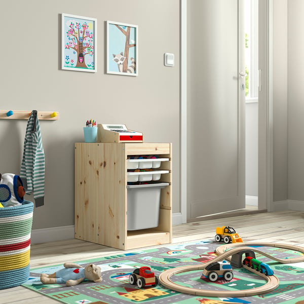 Aire de jeux pour enfants avec rangement de jouets TROFAST, peintures et jouets au sol.