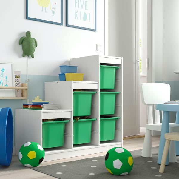 Unité TROFAST colorée : cadre blanc, bacs verts, accessoires bleus dans la salle de jeux pour enfants avec décor de tortue.