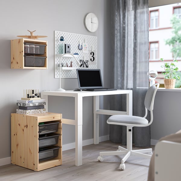 Bureau à domicile confortable avec des unités de rangement TROFAST, un bureau blanc, une chaise grise et des étagères en bois. Le bureau dispose d’un ordinateur portable et d’un panneau perforé avec des notes et des décorations.