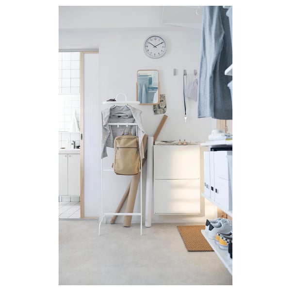 Entrée moderne avec des armoires TRONES blanches, un porte-manteau et une horloge au mur.