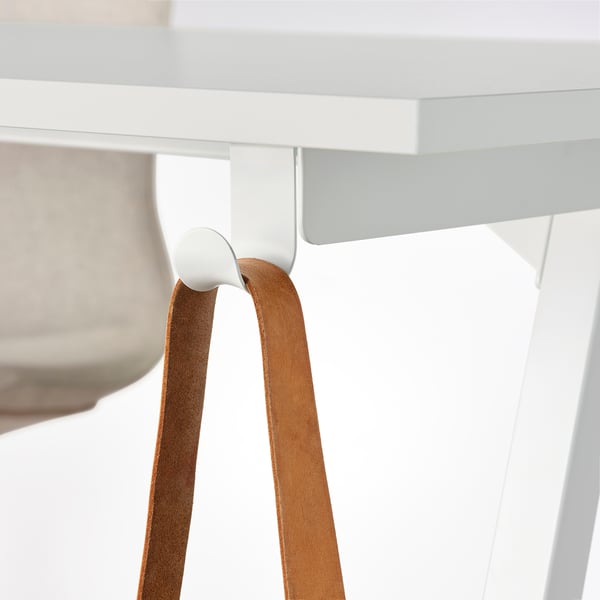 Bureau Trottén avec crochet blanc retenant une sangle en cuir marron pour le rangement.