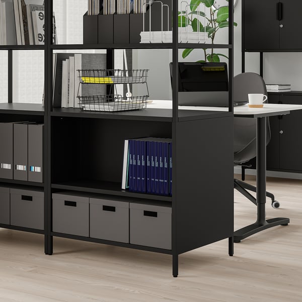 Unité de rangement de bureau noire avec rangement ouvert et fermé, accessible des deux côtés, stable sur des pieds réglables.
