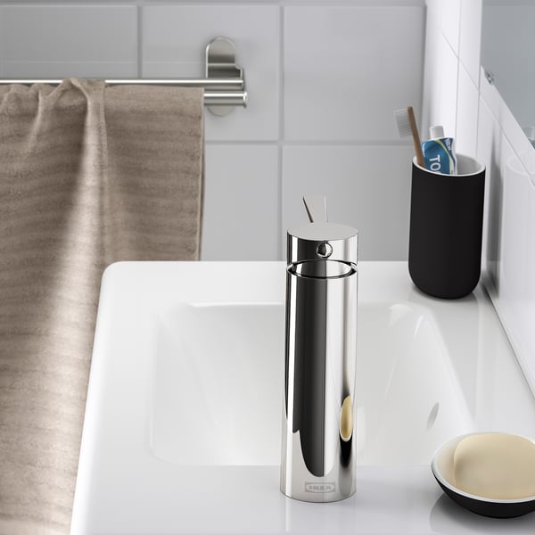 Un lavabo de salle de bain moderne avec un robinet élégant et un porte-brosse à dents noir sur un comptoir blanc.