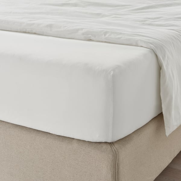 Un drap de lit blanc et impeccable avec des bords ajustés recouvrant soigneusement un matelas. Le tissu semble doux et respirant.