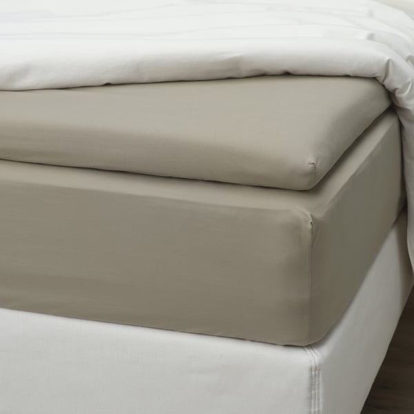 Lit avec drap-housse beige, bords élastiques, fils au pouce carré 79/cm², doux et respirant.