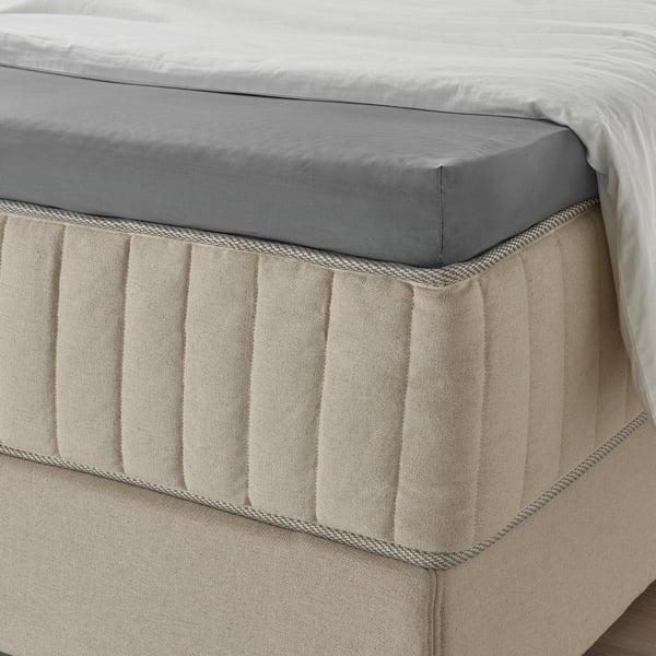 Drap-housse gris avec bords élastiques sur un matelas, démontrant sa capacité à s’adapter en toute sécurité sur un matelas épais.