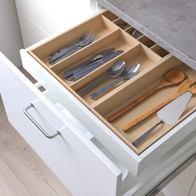 Tiroir de cuisine organisé avec couverts et ustensiles dans une armoire blanche.
