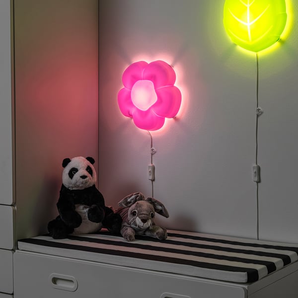 Deux peluches sur banc rayé, lampe fleur rose, lueur chaleureuse.