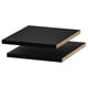 Deux étagères rectangulaires noires, empilées, avec des surfaces lisses et des bords robustes. Le design est élégant et moderne.