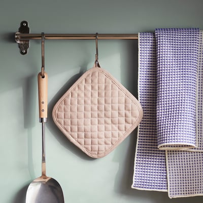 Rangement de cuisine moderne avec manique en vålvårdad en diamant beige, serviette à carreaux et louche en métal.