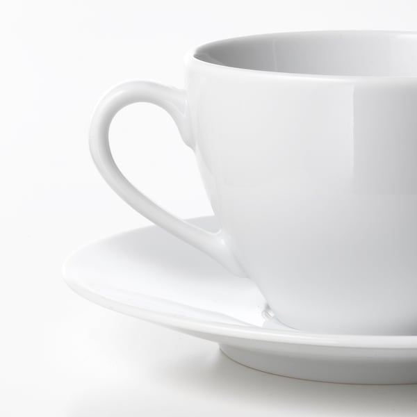 Tasse en porcelaine blanche de haute qualité, anse lisse, repose sur une soucoupe assortie.