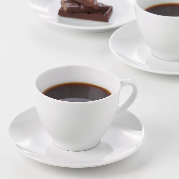 Deux tasses de café en porcelaine blanche sur soucoupes, durables et conçues pour un usage quotidien et formel.