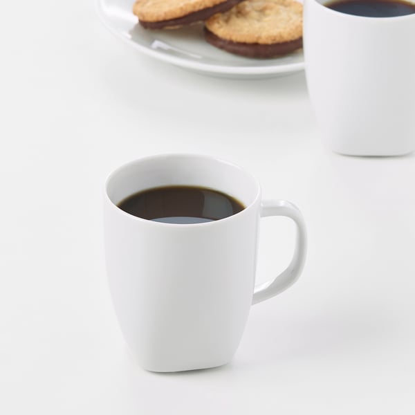 Deux tasses de café blanc à côté d’une assiette de biscuits. Tasses en porcelaine feldspath durable et résistante aux chocs.