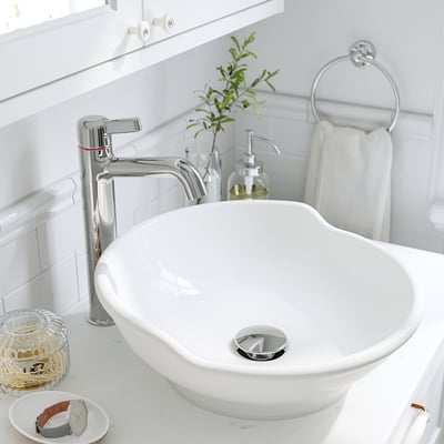 Évier blanc moderne avec robinet chromé, cuve ronde, dossier et drain assorti.