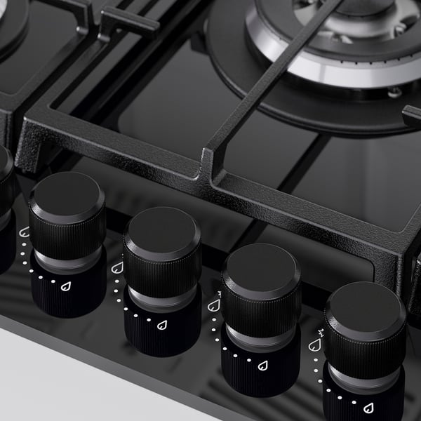 Cuisinière à gaz avec 5 boutons noirs. Surface en verre, supports en fonte robustes.