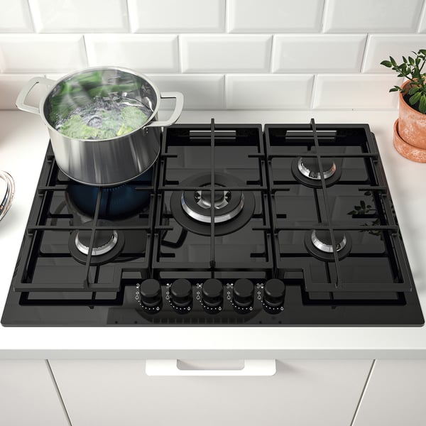 Cuisinière à gaz avec cinq brûleurs, légumes bouillants, supports en fonte, surface vitrée.