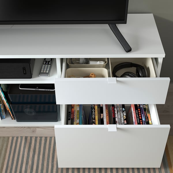 Meuble TV blanc avec étagères ouvertes contenant des livres et des médias, tiroirs de rangement.