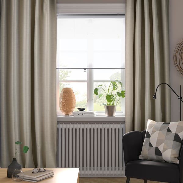 Chambre confortable avec rideaux gris VILBORG, chaise noire, plante de style, lampe et livres.