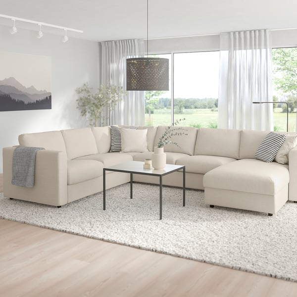 Salon moderne avec sectionnel VIMLE, table basse noire, grande fenêtre, tapis et couverture.