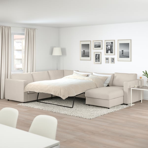 Espace de vie moderne avec canapé-lit séparé VIMLE beige, oreillers, tapis et art mural.
