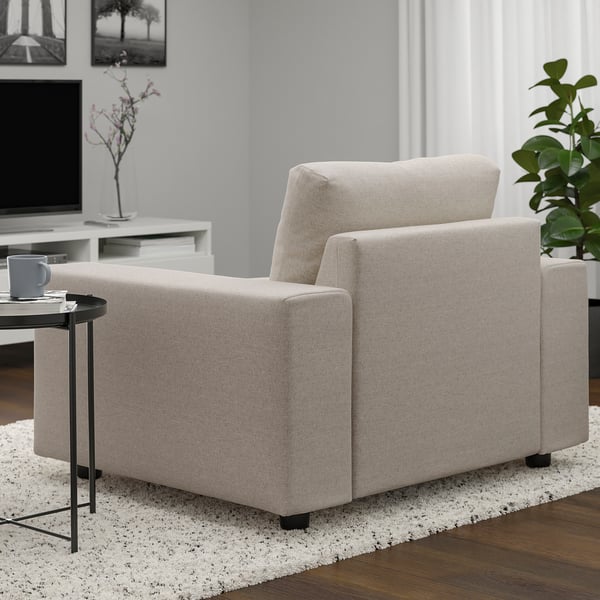 Salon moderne avec canapé VIMLE beige, table d’appoint noire, tapis gris, plante et télévision.