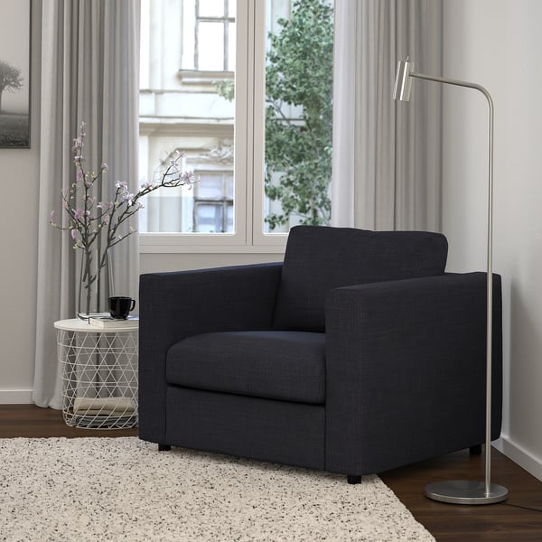 Salon moderne avec fauteuil VIMLE, fenêtre, tapis, table d’appoint avec fleurs de cerisier.