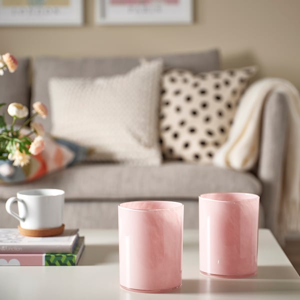 Bougeoirs roses sur la table avec tasse à café, livres et canapé.