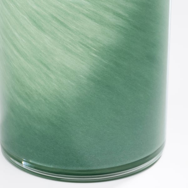Vase cylindrique en verre vert, fabriqué à la main avec une surface lisse et réfléchissante, se suffit à lui-même.