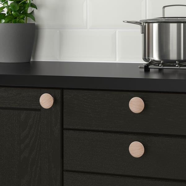 Armoire noire avec boutons et plante en bois.