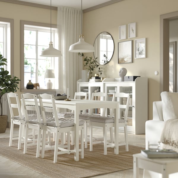 Salle à manger avec meubles blancs, chaises VIPPÄRT, suspensions, miroir, étagère et grandes fenêtres.