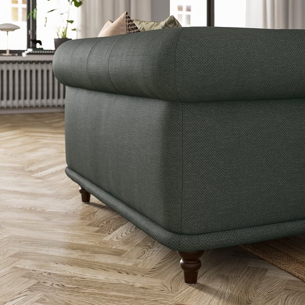 Fauteuil VISKAFORS vert aux formes rondes et à l’assise moelleuse ; mélange de coton, de polyester et de viscose ; Pieds robustes en bois foncé.