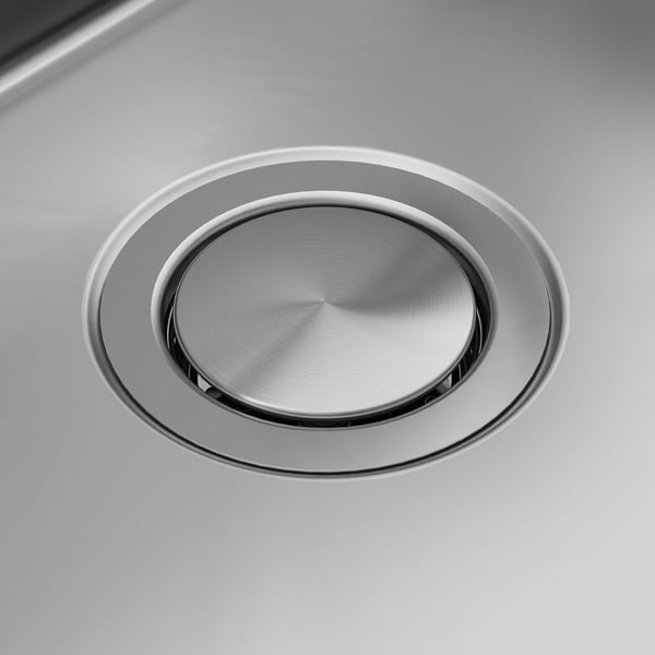 Couvercle de vidange d’évier en acier inoxydable. Surface lisse et polie. Forme circulaire avec un léger bord biseauté. Le centre a une texture circulaire subtile.
