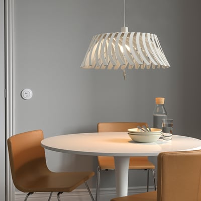 La suspension YTLÄGE blanche, design orientable, est suspendue au-dessus d’une petite table à manger avec des chaises.