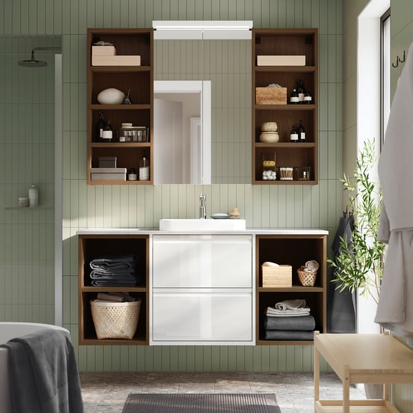 Moderne ÄNGSJÖN badkamermeubel met spiegel, planken, handdoeken en toiletartikelen. Sereen met groene muren.