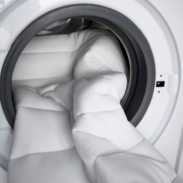 Witte gevel van opgerold ÅFJÄLL-matras, met getextureerde bekleding en comfortlagen.