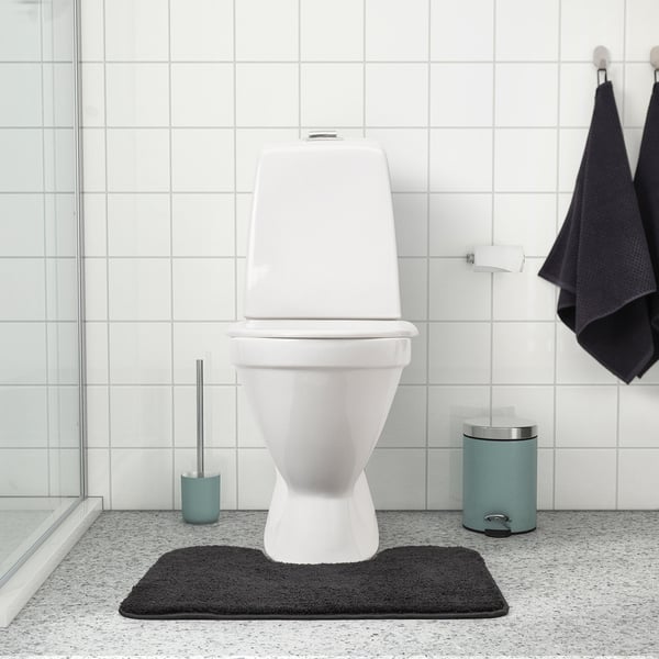 Wit toilet op zwarte mat, aquabrush en prullenbak. Mat: BACKMÅRA, donkergrijs, 100% polyester, dik, zacht.