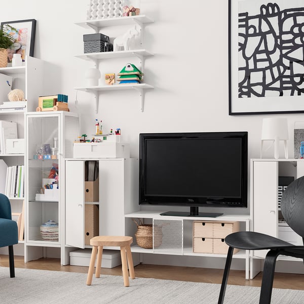 Minimalistische woonkamer met wit tv-meubel, houten krukken en versierde planken.