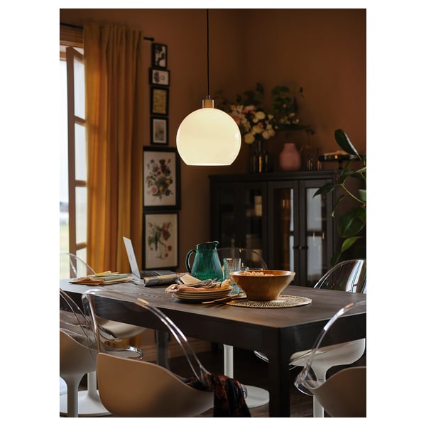 Moderne eethoek met houten tafel, witte draaistoelen, hanglamp, planten en decor.