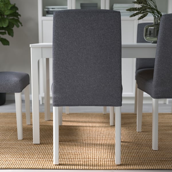 Drie moderne stoelen rond een tafel met grijze bekleding en witte poten, ontworpen om comfortabel te zitten.