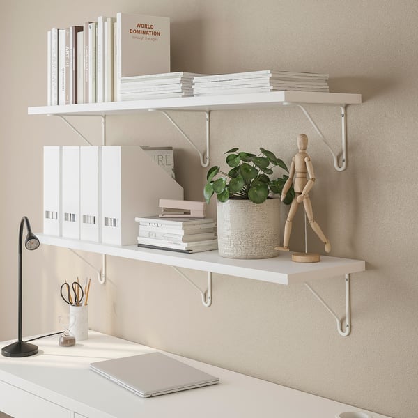 Witte wandplanken met boeken, ordners, een potplant en een houten figuur.