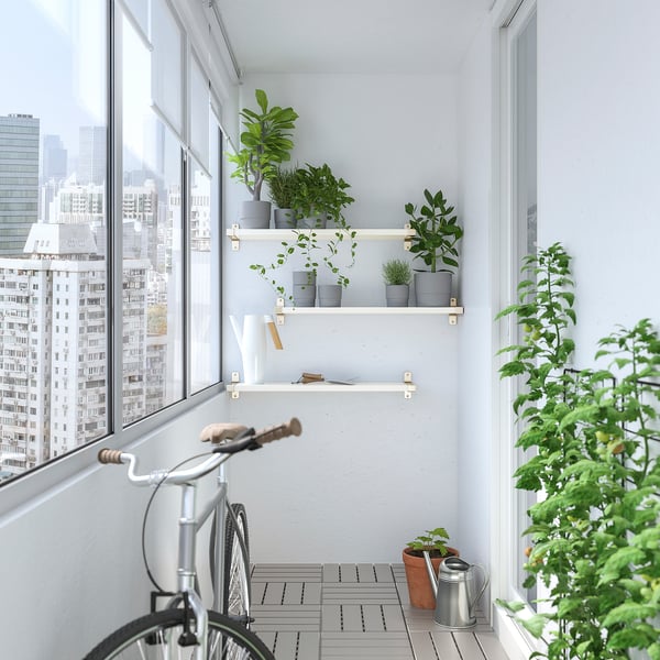 Stadsbalkon met planten, fiets en stedelijke skyline.