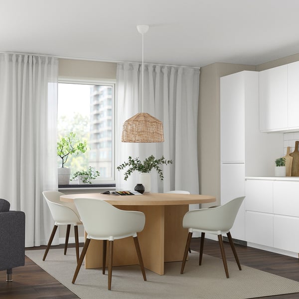 Moderne eetkamer met een strakke tafel, vier stoelen, hanglamp, planten en 3D-pleisterwerk.