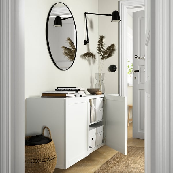 Witte wandkast met open deuren, met verstelbare planken en items zoals boeken en een mand.