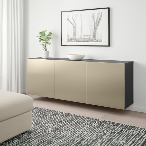 Moderne woonkamer met BESTÅ wandkast in lichtbruin en zwart, tussen bank en gestreept vloerkleed, met plant en schaal erop.