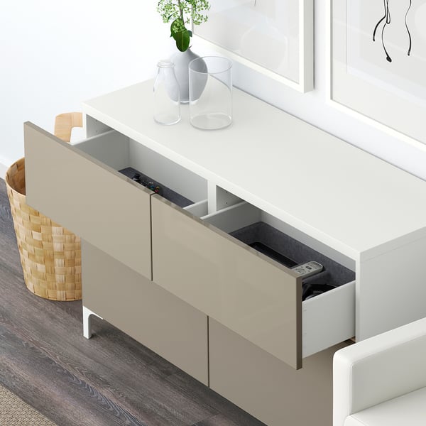 Wit BESTÅ opbergmeubel met open lade, afstandsbediening en decoratieve voorwerpen aan de bovenkant.