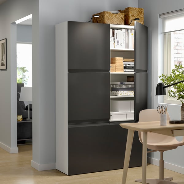 Moderne leefruimte met zwart BESTÅ opbergmeubel, witte deuren, verstelbare planken, houten vloer, witte stoel en bureaulamp.