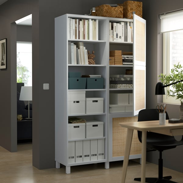Een moderne opbergruimte met open en gesloten gedeelten, met boeken, dozen en decor, gelegen naast een bureau met een stoel.