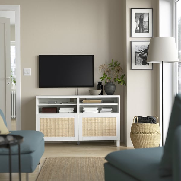 Moderne woonkamer met BESTÅ tv-meubel, flatscreen-tv, boeken, inrichting, zwart-witfoto's, vloerlamp en blauwe stoelen.