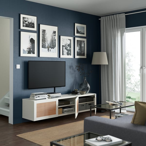 Moderne woonkamer met donkerblauwe muren met BESTÅ tv-meubel, flatscreen-tv, foto's, glazen salontafel en groot raam.