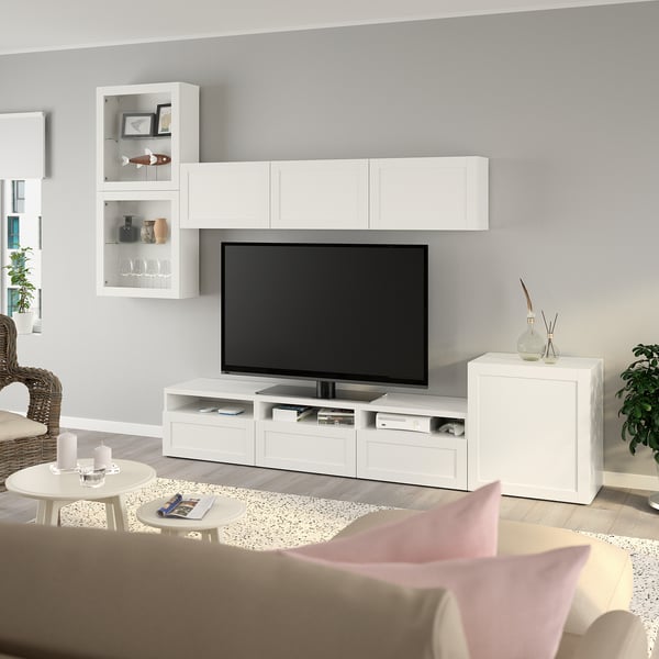 Moderne BESTÅ tv-opstelling met opbergruimte, salontafel en rieten stoel in een schone woonkamer.